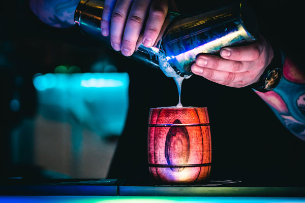 Bartender mixing up a drink that looks like the barrels in Donkey Kong.