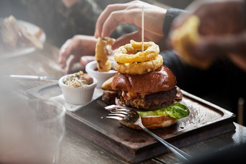 A juicy burger with onion rings on top.